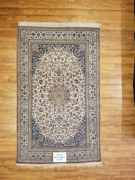 Rectangular Persian rug with floral pattern, ivory and navy colors, on wood floor.