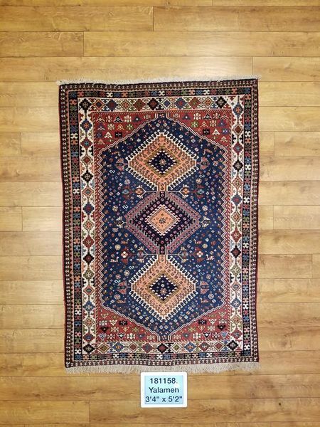 Blue, red, and beige oriental rug with diamond-shaped motifs on a wooden floor.