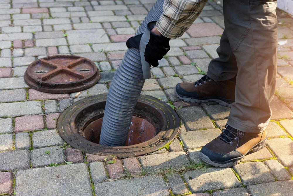 A man is pumping a hose into a manhole cover.