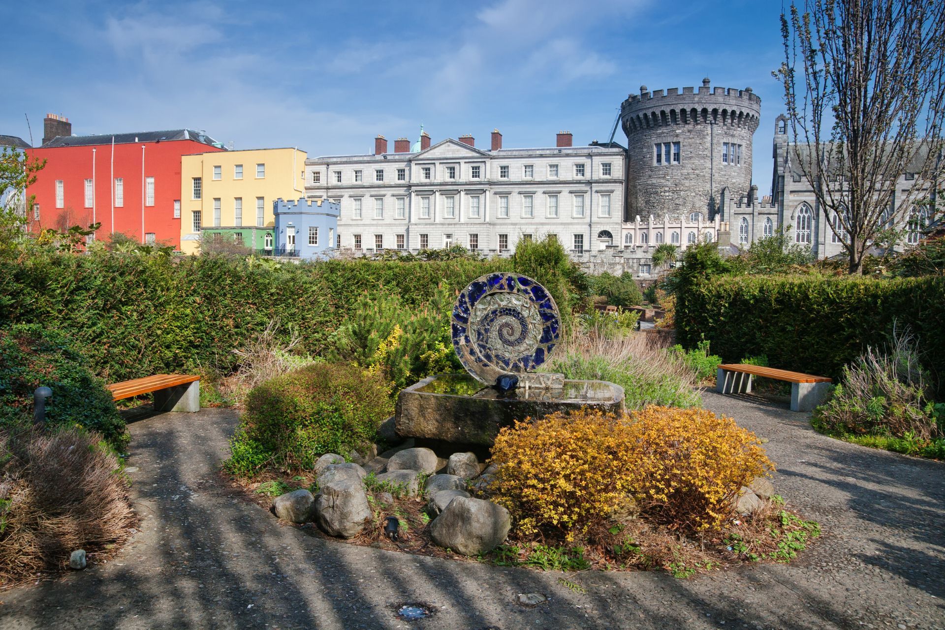a park with dublin castle in the background and a spiral sculpture in the foreground