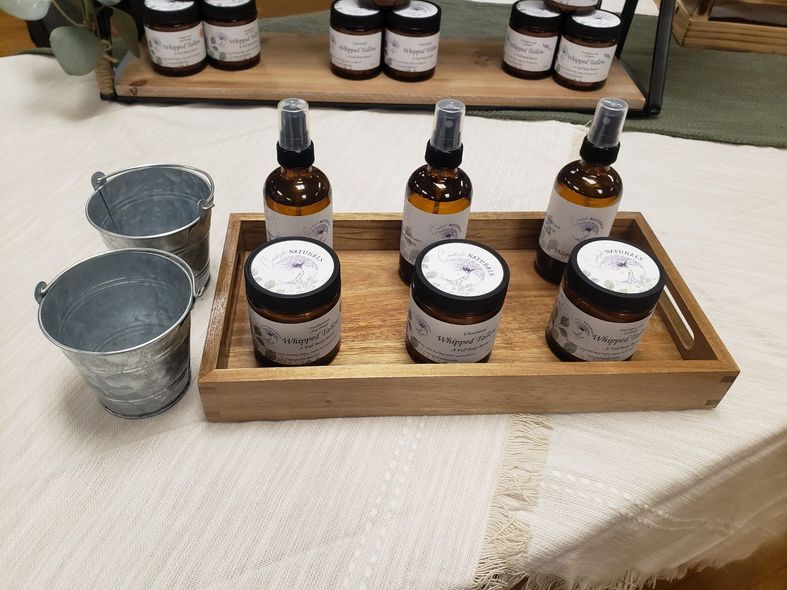 A wooden tray filled with bottles and jars on a table.