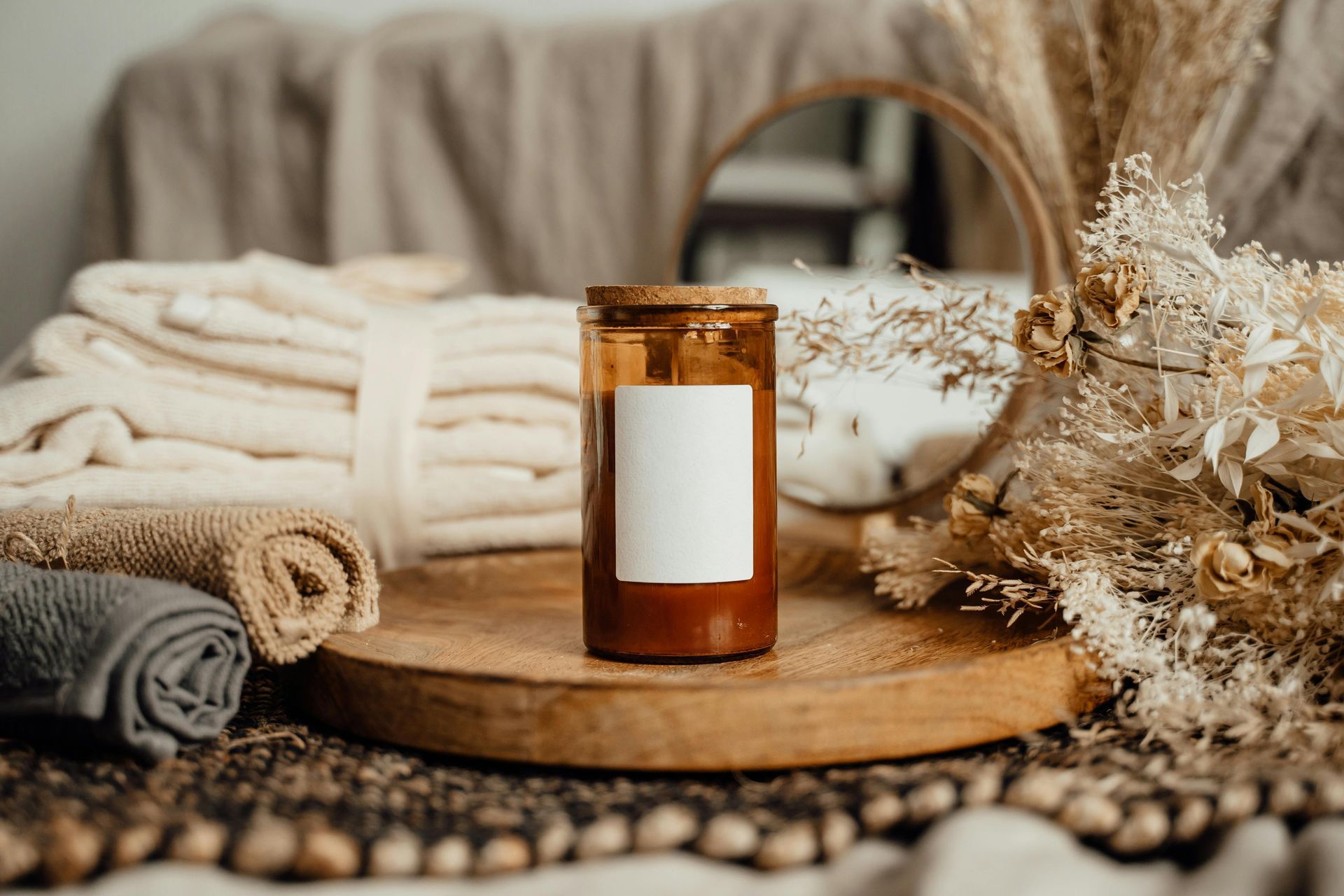 A candle is sitting on a wooden tray next to towels and flowers.