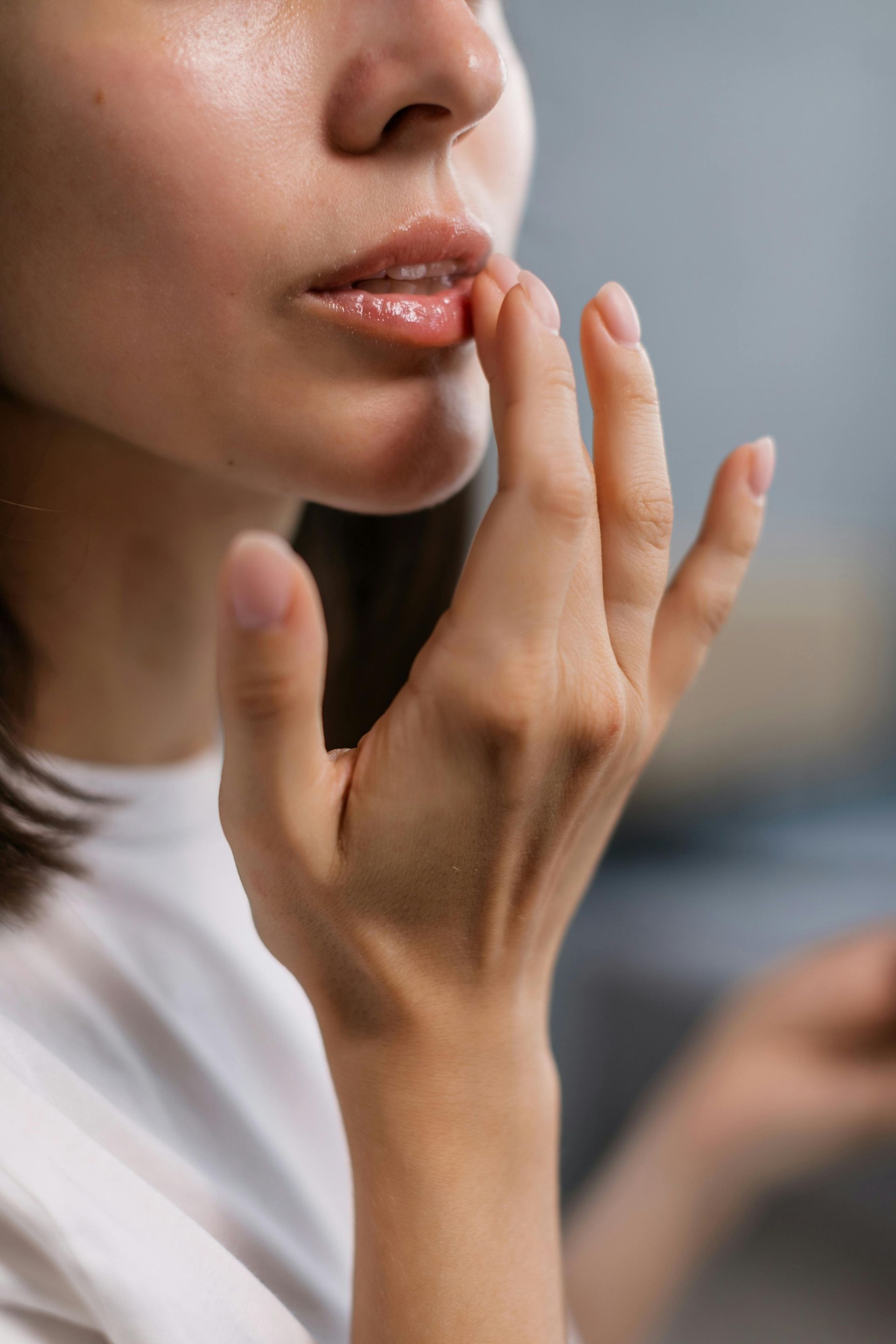 A woman is applying lip balm to her lips with her finger.