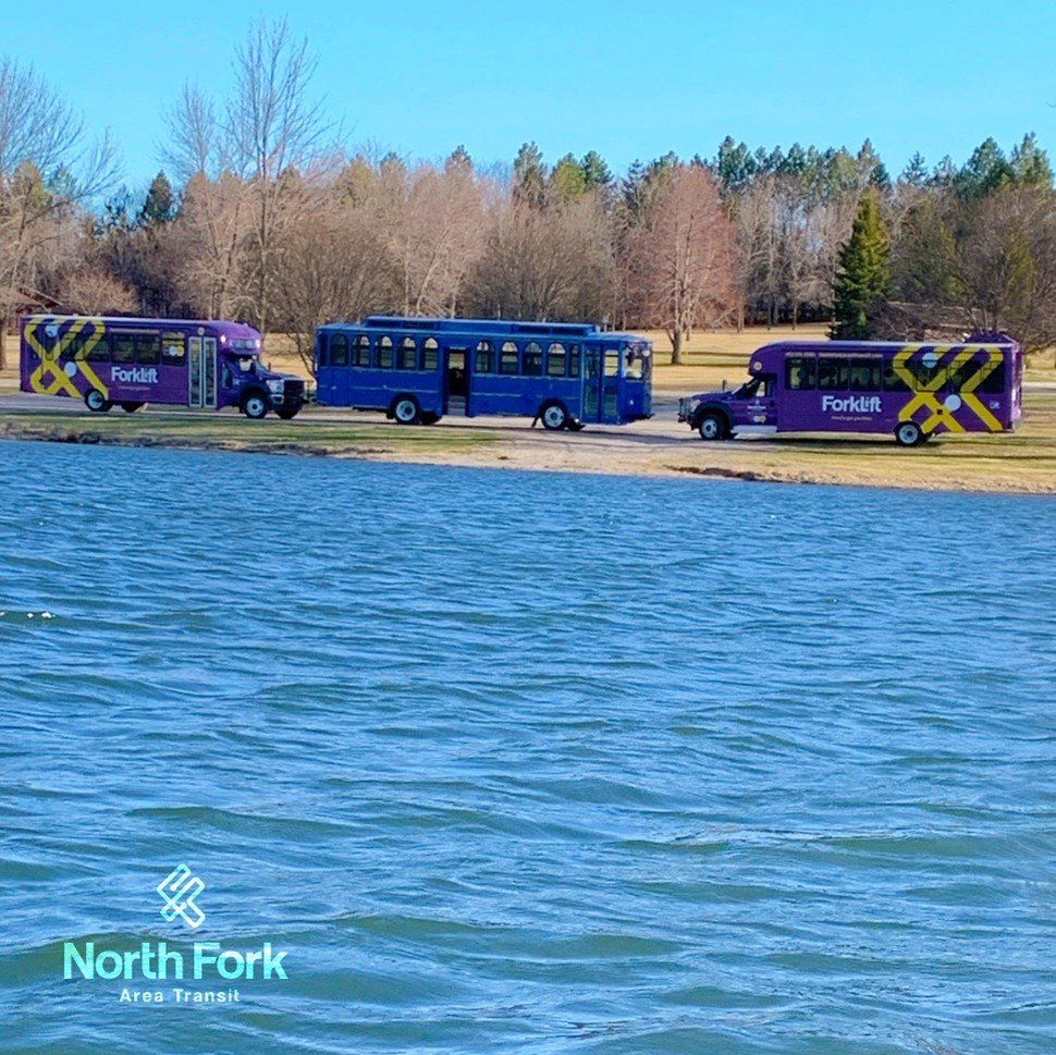 North Fork Area Transit passenger busses and trolley by Skyview Lake in Norfolk