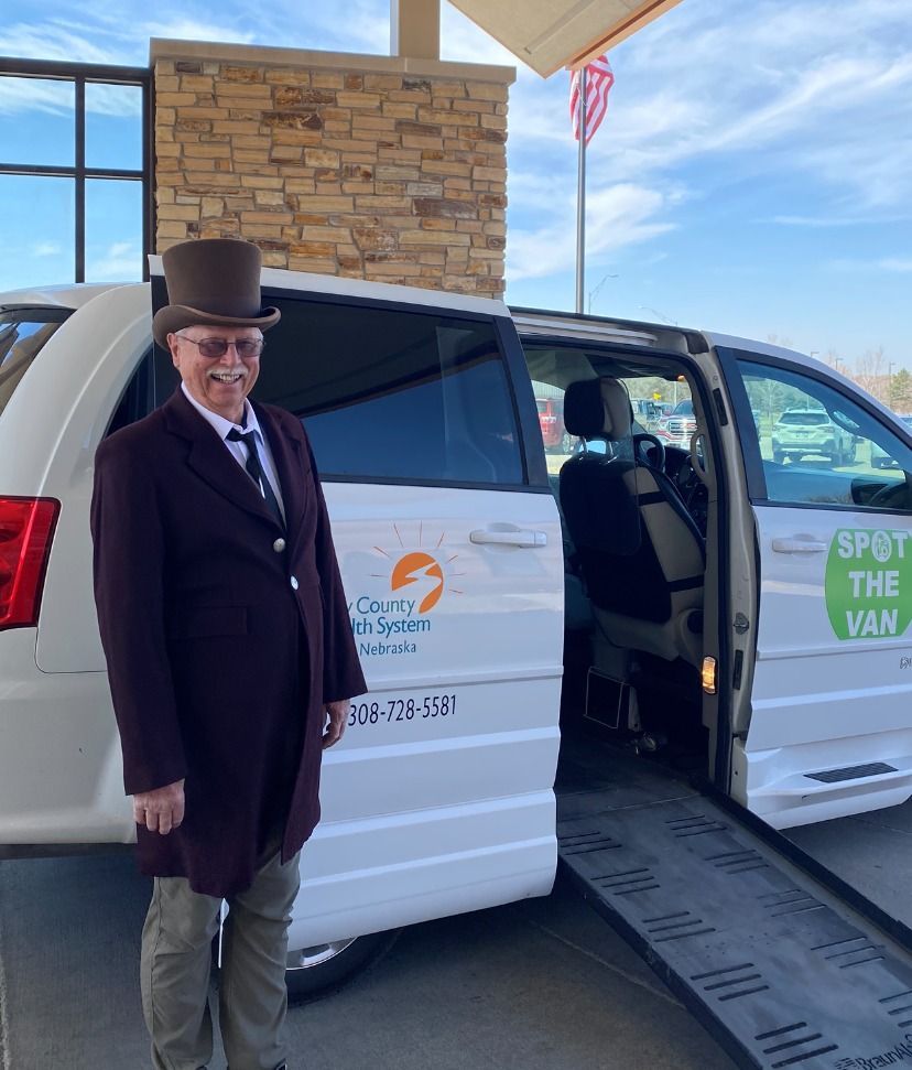 photo of a driver dressed in a suit and top hat standing in front of a van