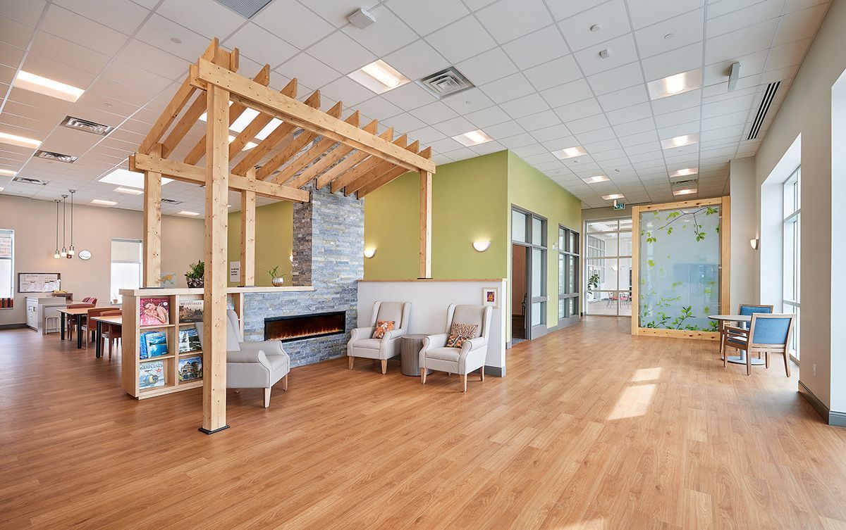 A large room with wooden floors , chairs , tables and a fireplace.