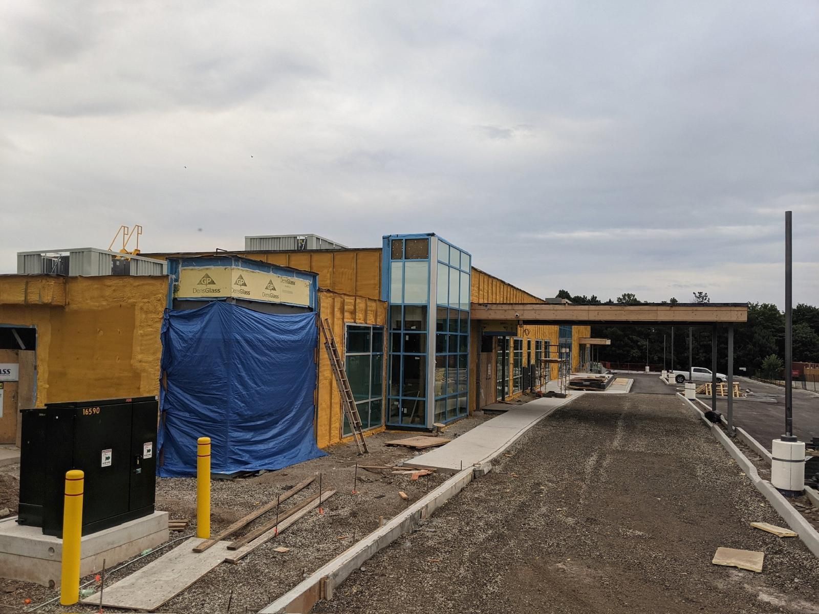 A building under construction with a blue tarp on the side of it.