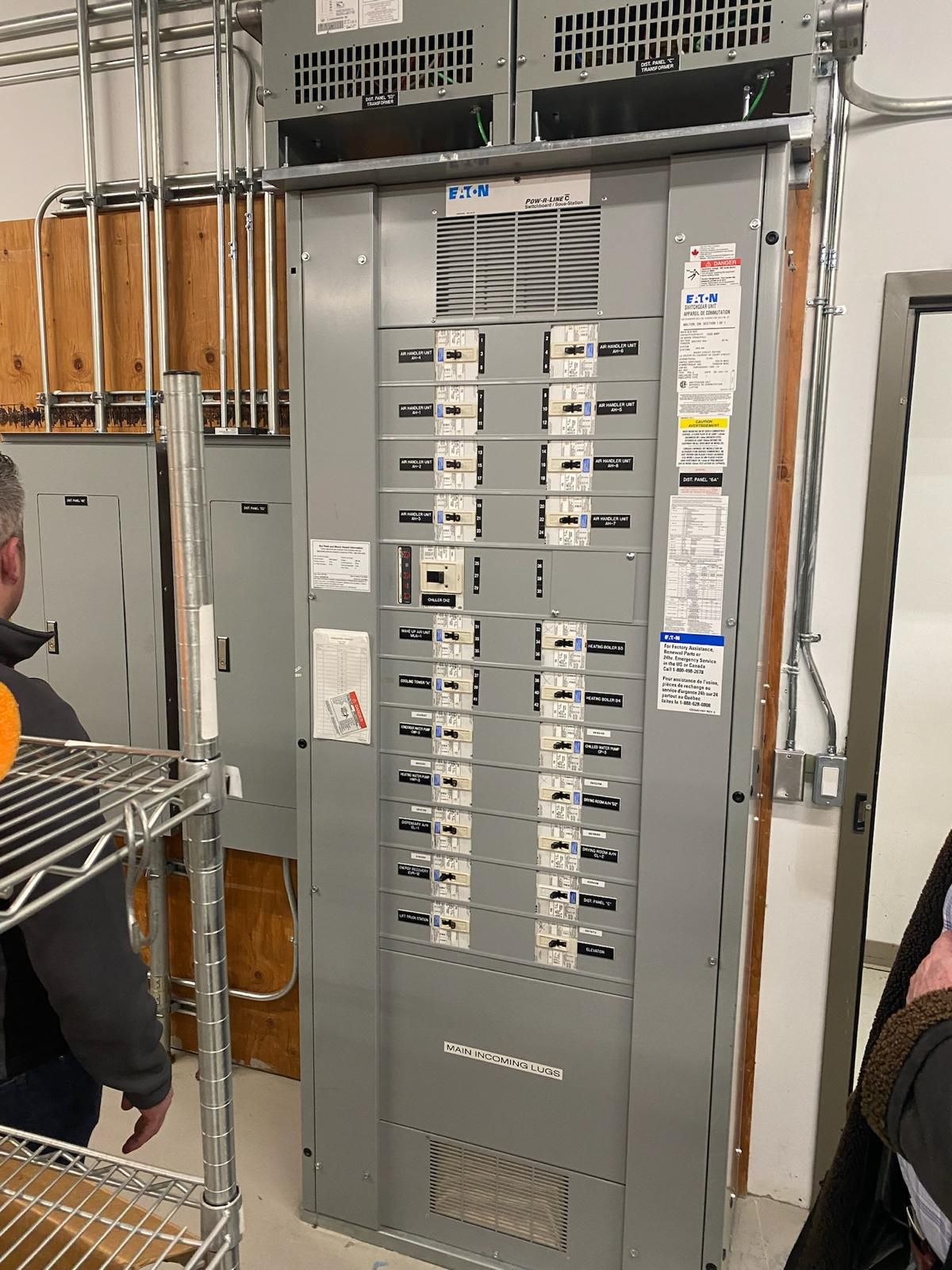 A man is standing next to a large electrical box in a room.