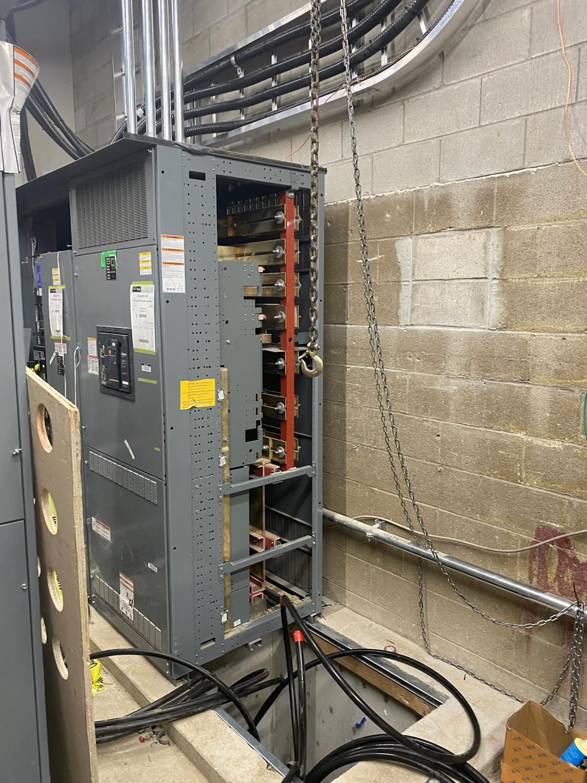 A large electrical box is sitting in a room next to a brick wall.