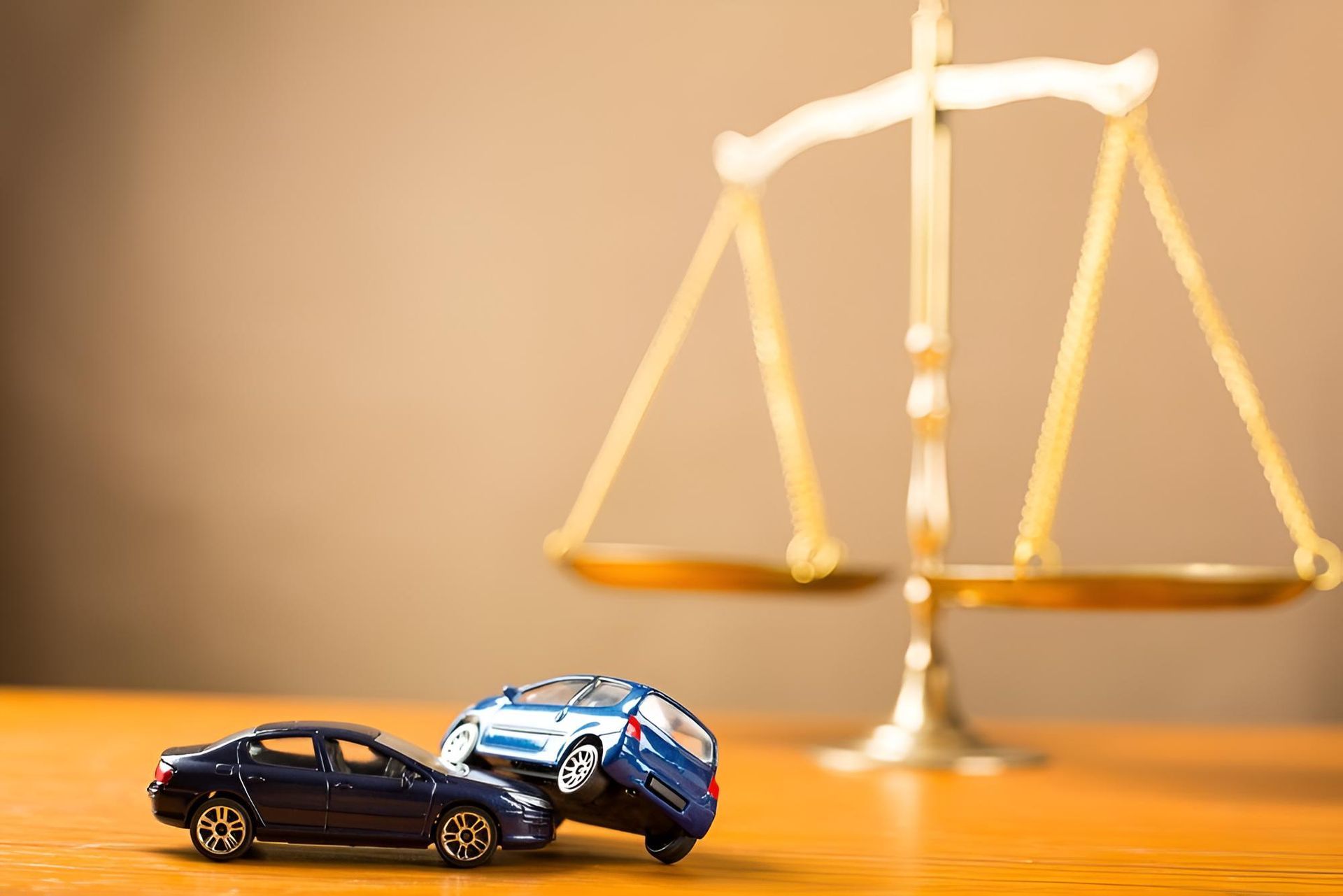 A Toy Car is Sitting on a Wooden Table Next to a Scale of Justice — Bradley J Bragg - Solicitor in Atherton, QLD