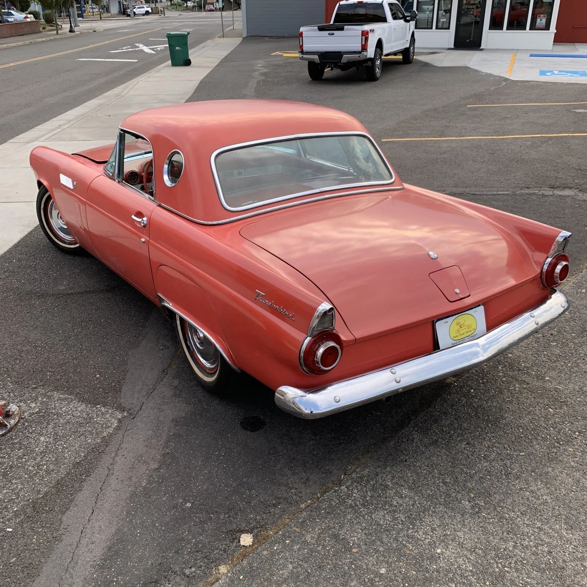 Red vintage Ford Thunderbird, parked next to a street.