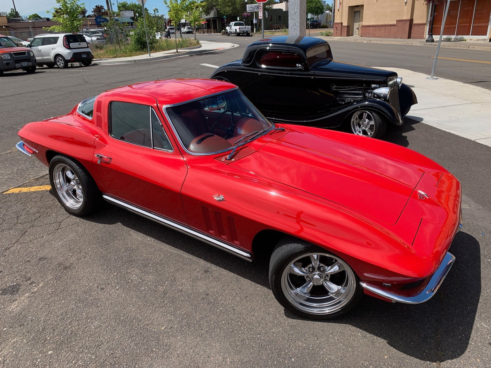a red corvette is parked next to a black car