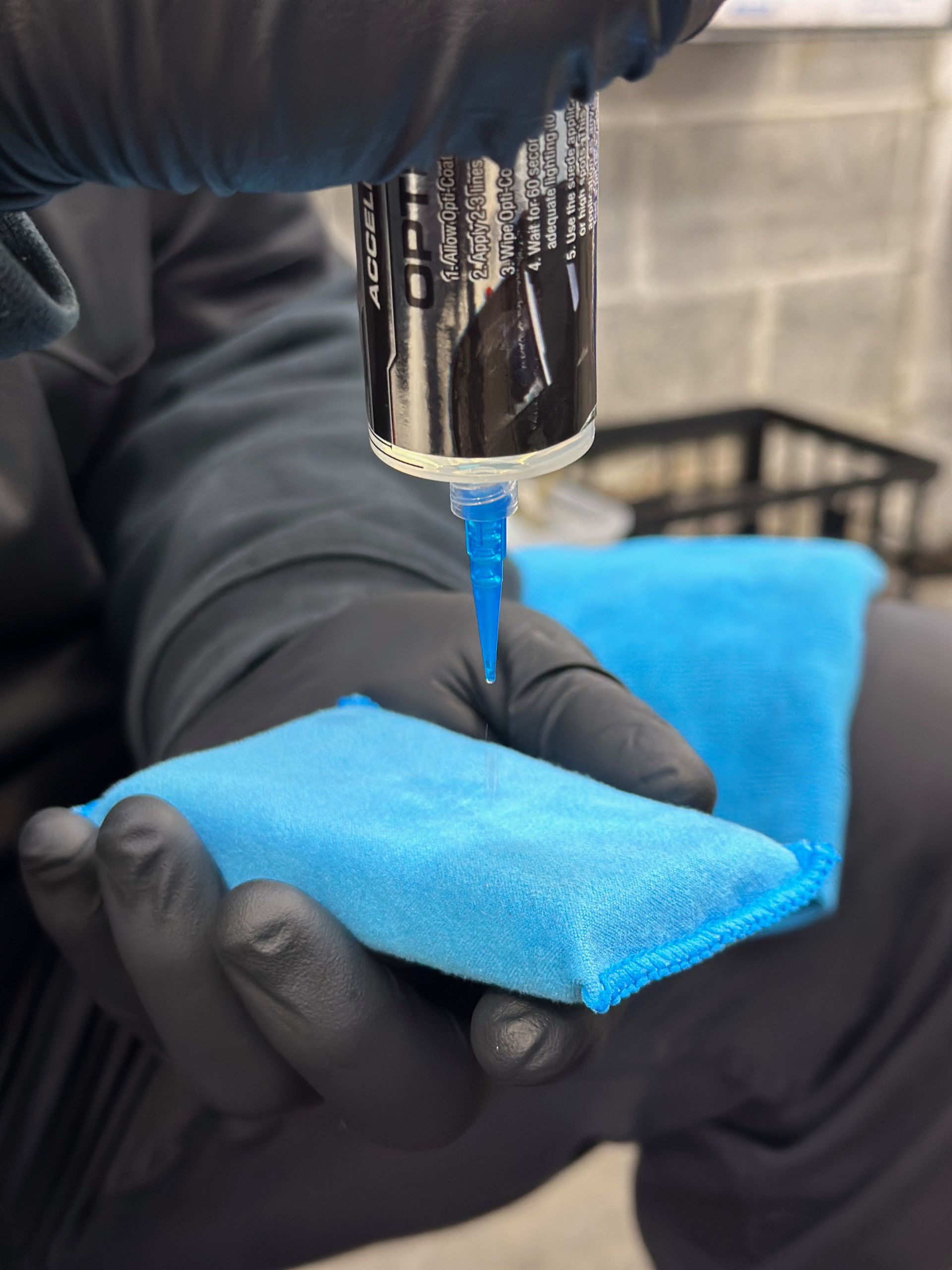 Gloved hands dispensing blue liquid from a tube onto a blue sponge.