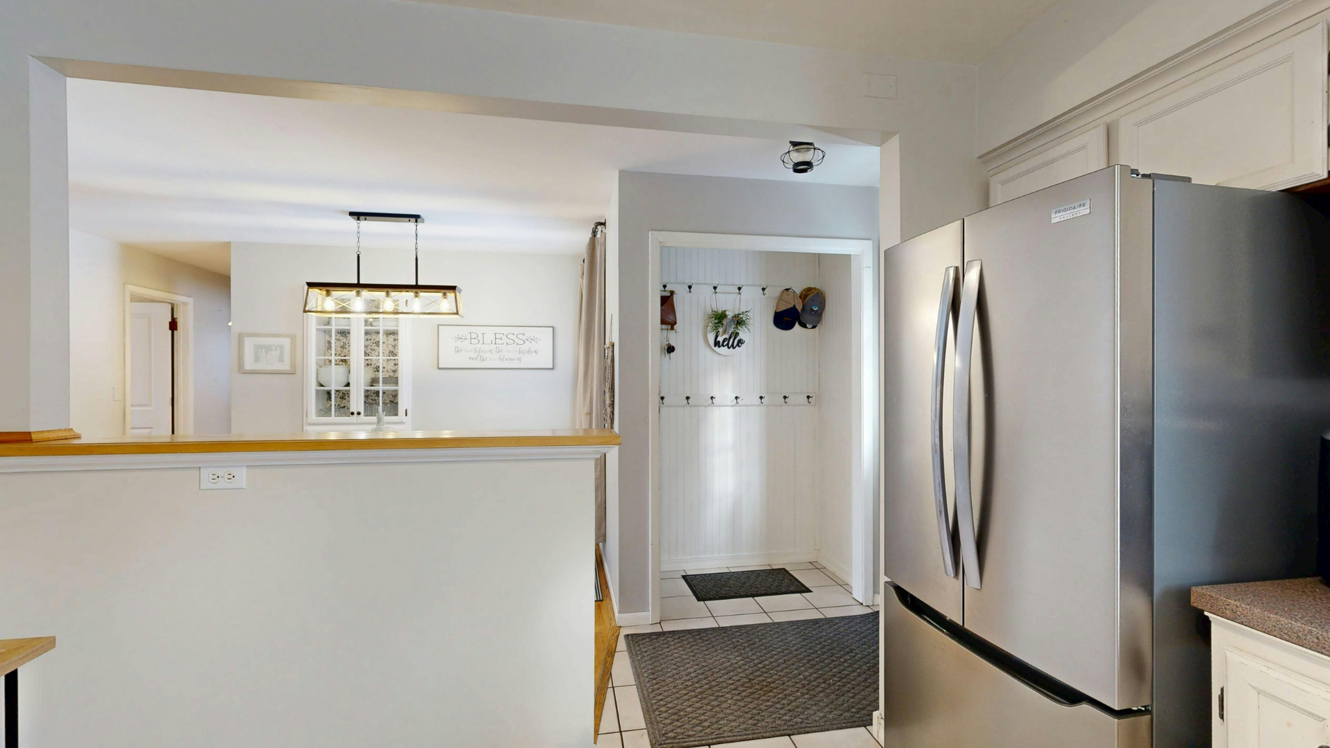 Interior kitchen view with stainless steel refrigerator, doorway to hallway, and opening into a dining area.