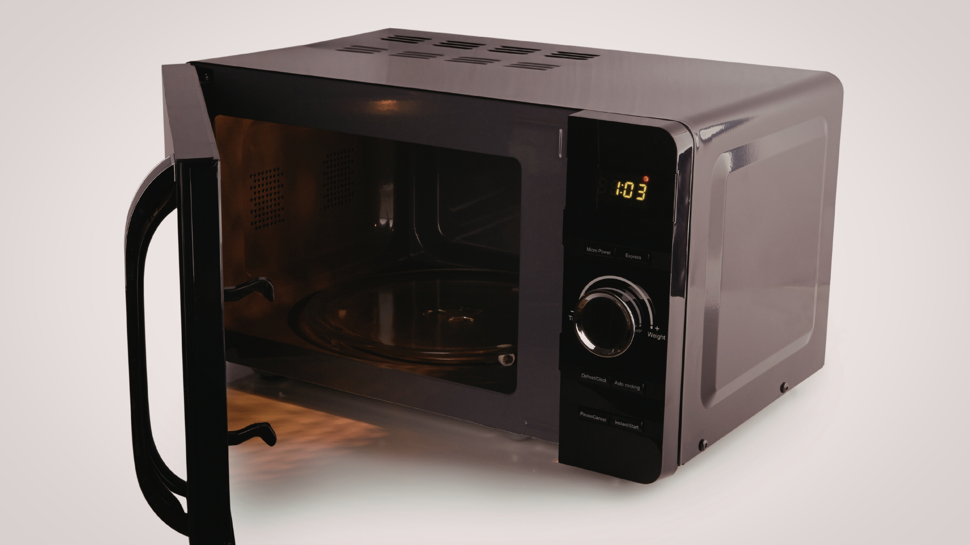 Black microwave oven, door open, on a light surface.