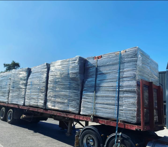 A red semi truck is loaded with lots of boxes