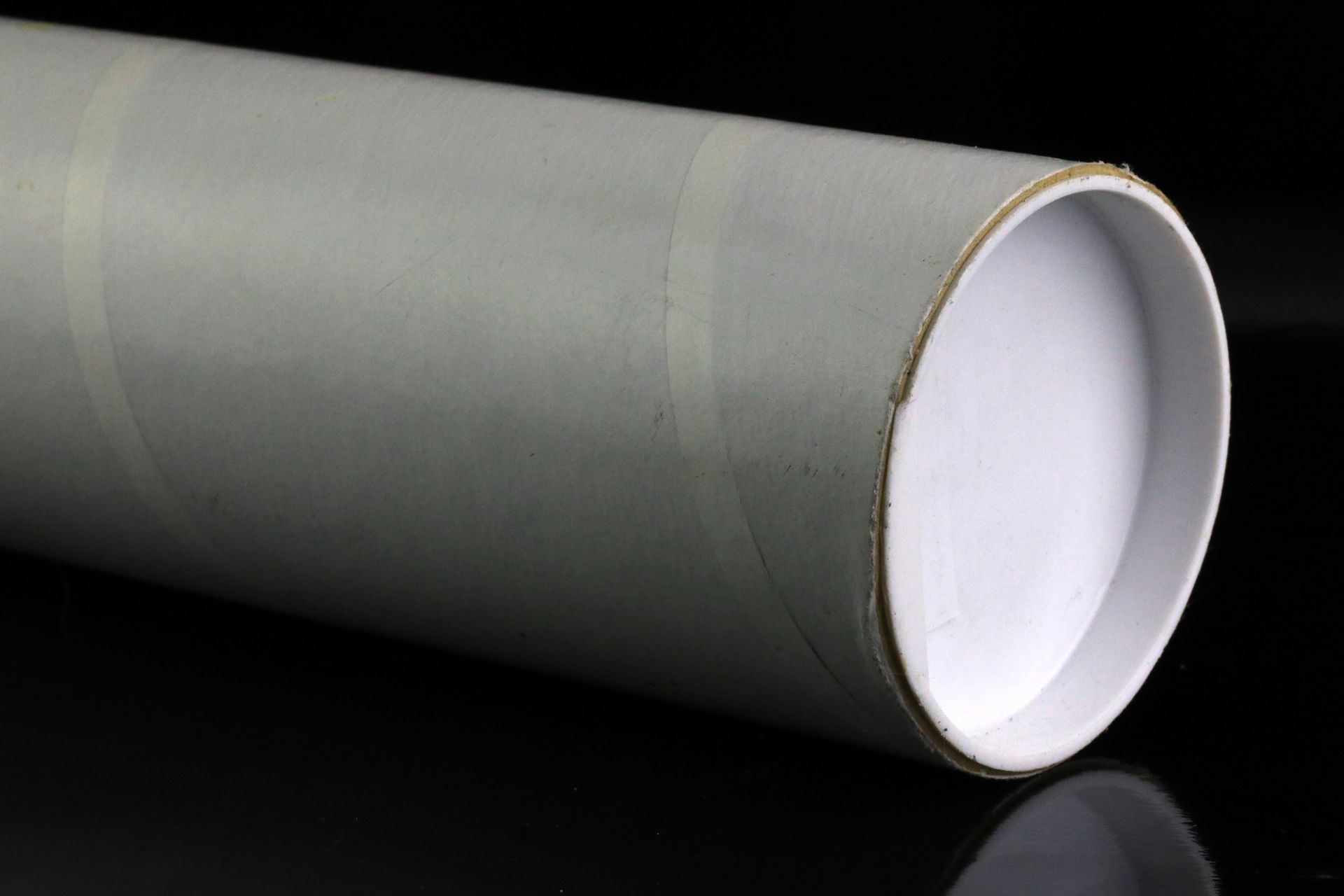 Close-up of a white mailing tube, showcasing its smooth surface and cylindrical shape for packaging.