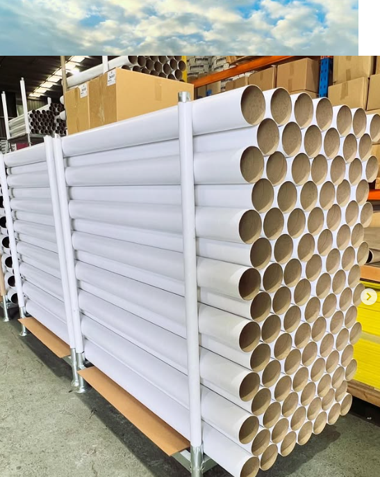 A truck is carrying a lot of pipes on the back of it.