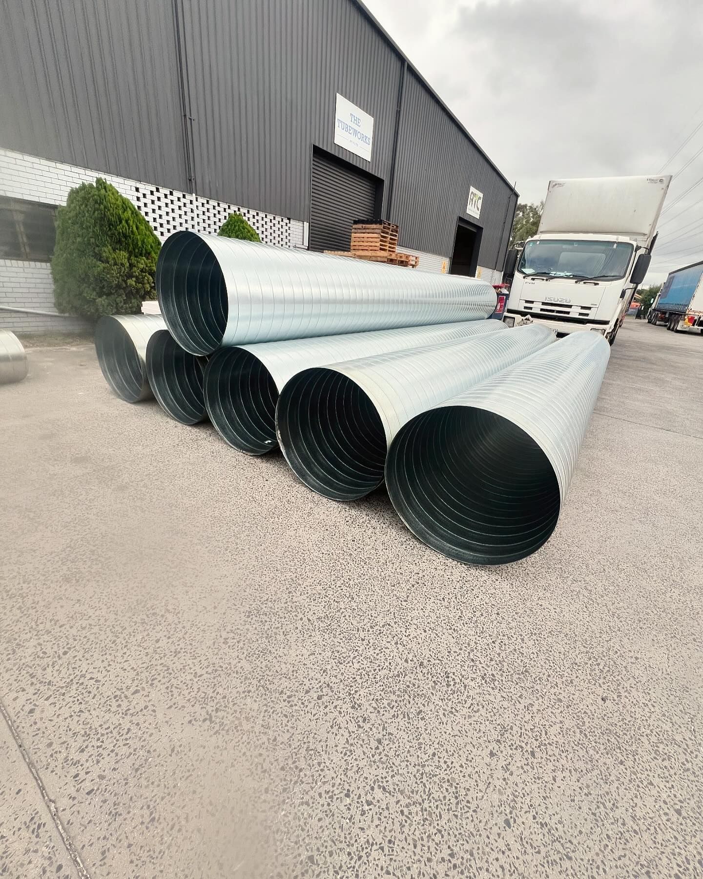 A bunch of metal pipes are stacked on top of each other in front of a building.