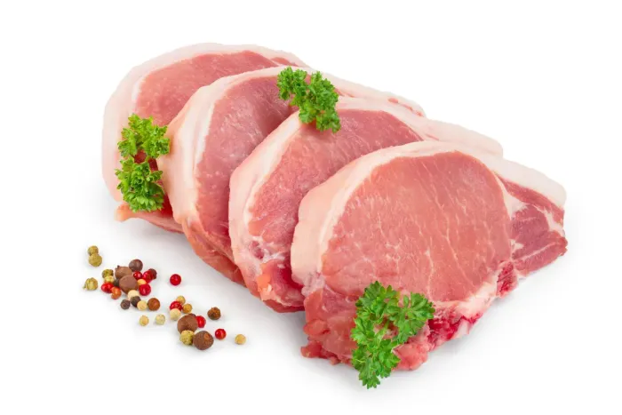 raw pork chops with parsley and pepper on a white background .