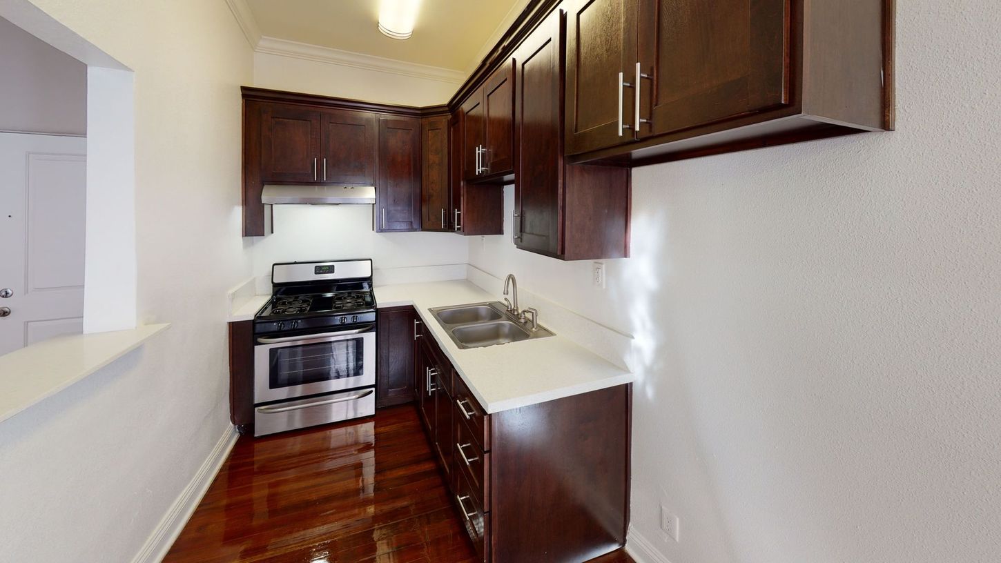 Small kitchen with dark cabinets, stainless steel appliances, and white countertops.