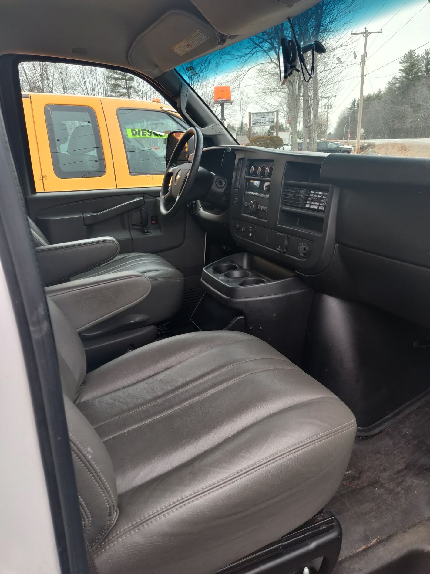 The interior of a van with a yellow truck in the background.