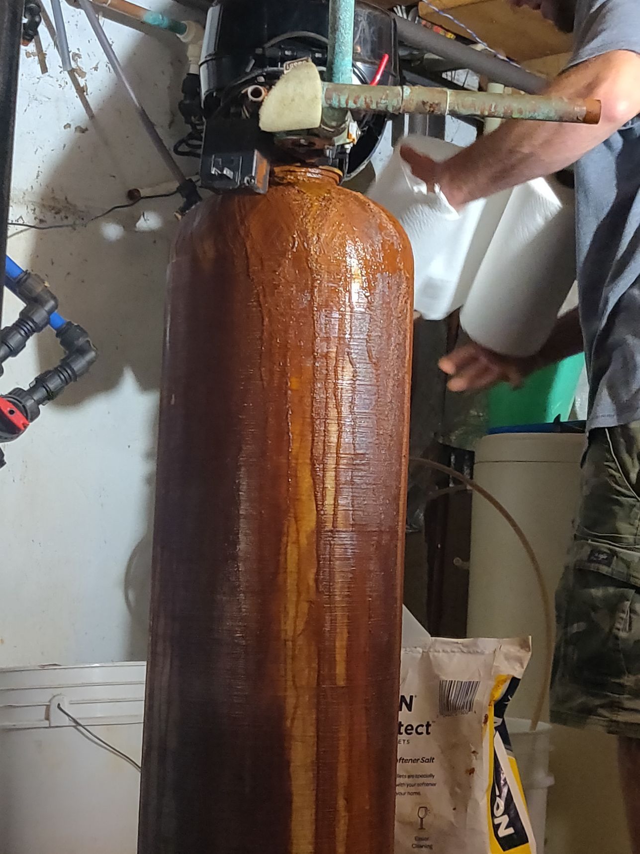 A man is working on a water filter in a basement.