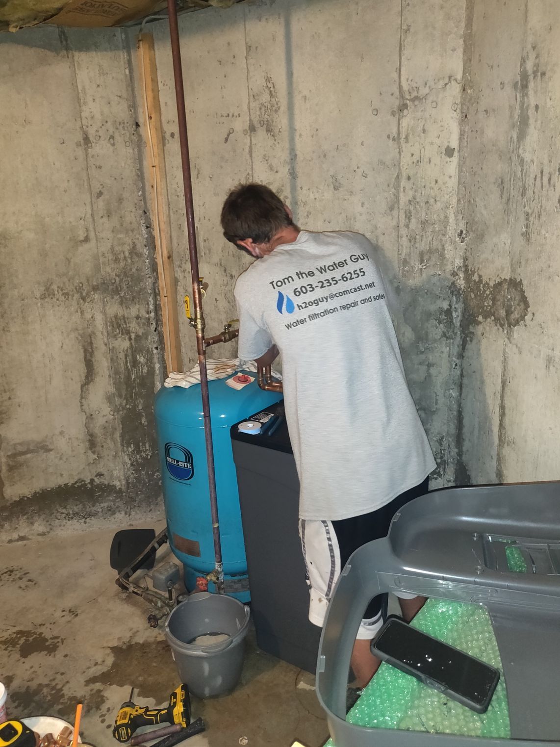 A man is working on a water heater in a basement.