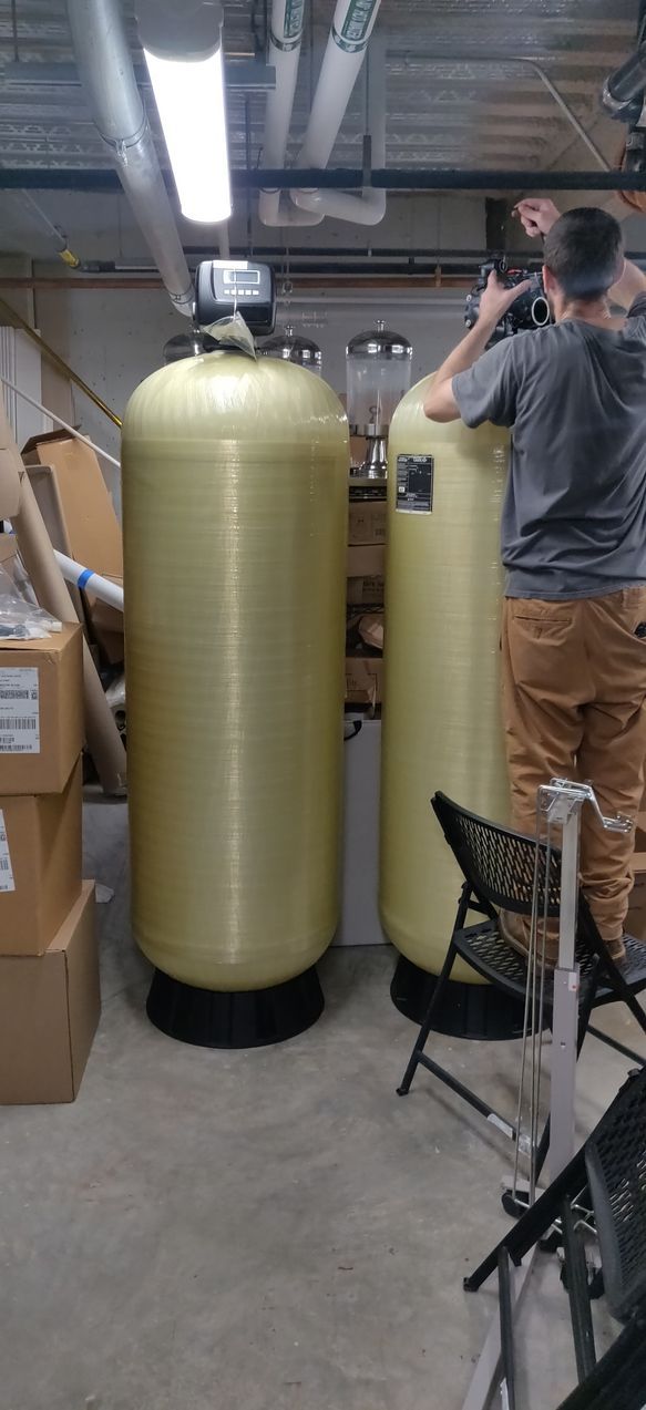 A man is standing next to two large tanks in a room.