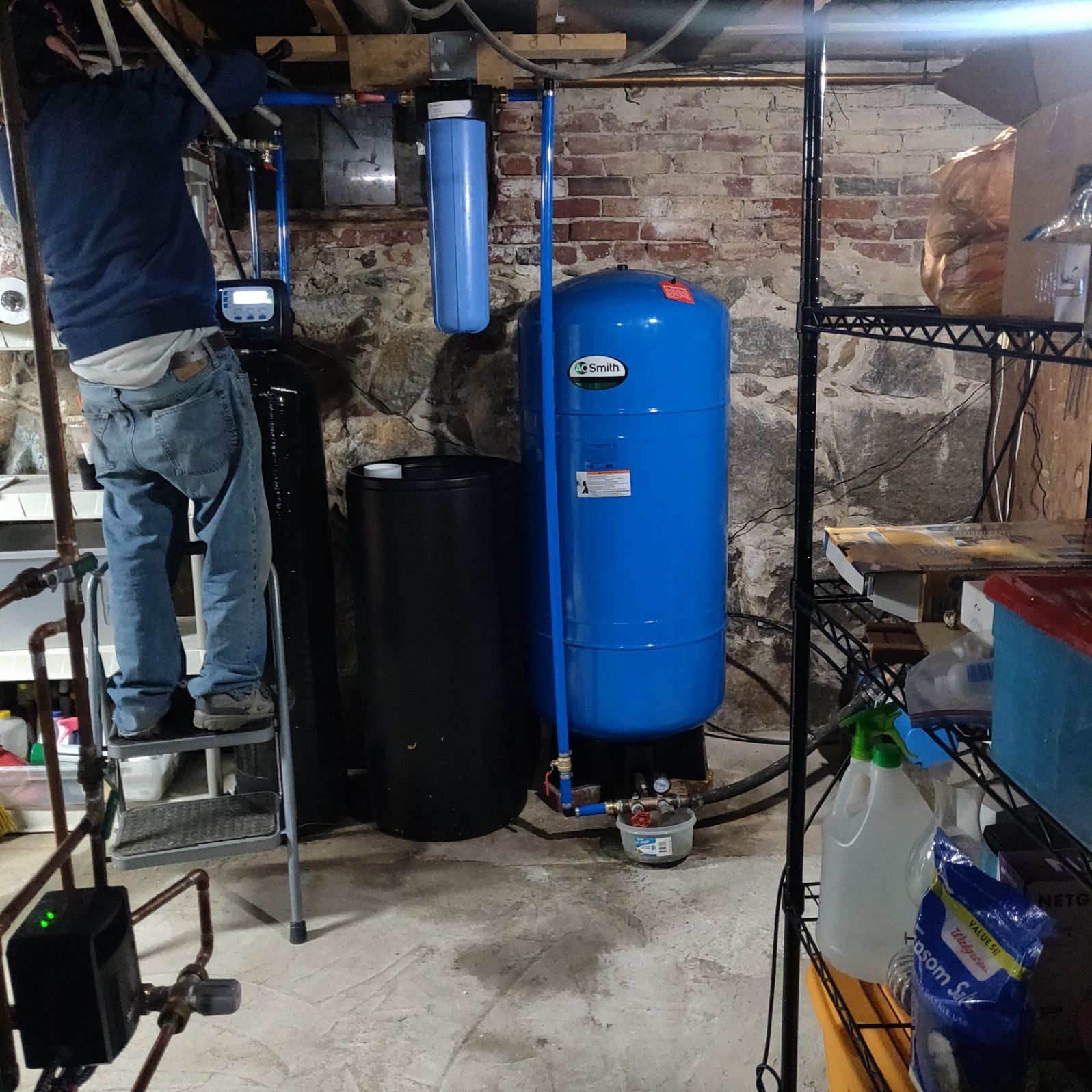 A man standing on a ladder working on a blue tank