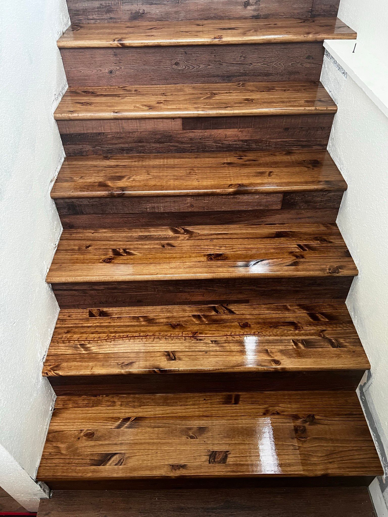 A wooden staircase with a white wall in the background.