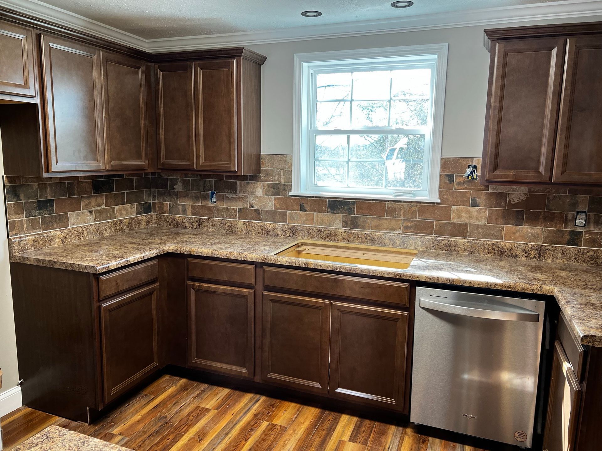 A kitchen with wooden cabinets , granite counter tops , and a stainless steel dishwasher.