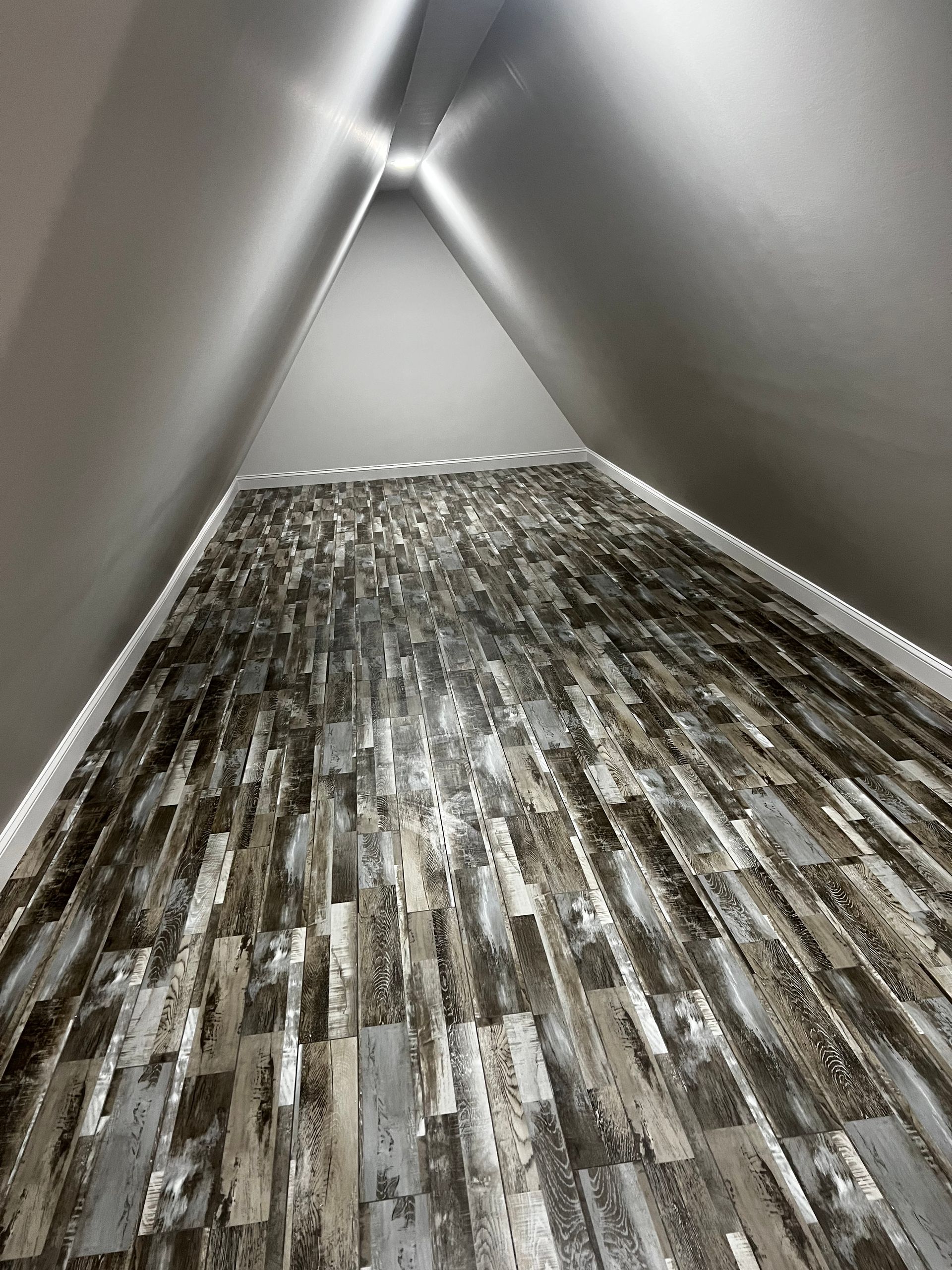 A hallway with a wooden floor and a triangle shaped ceiling.