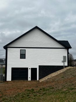 A white house with black trim and a black garage door