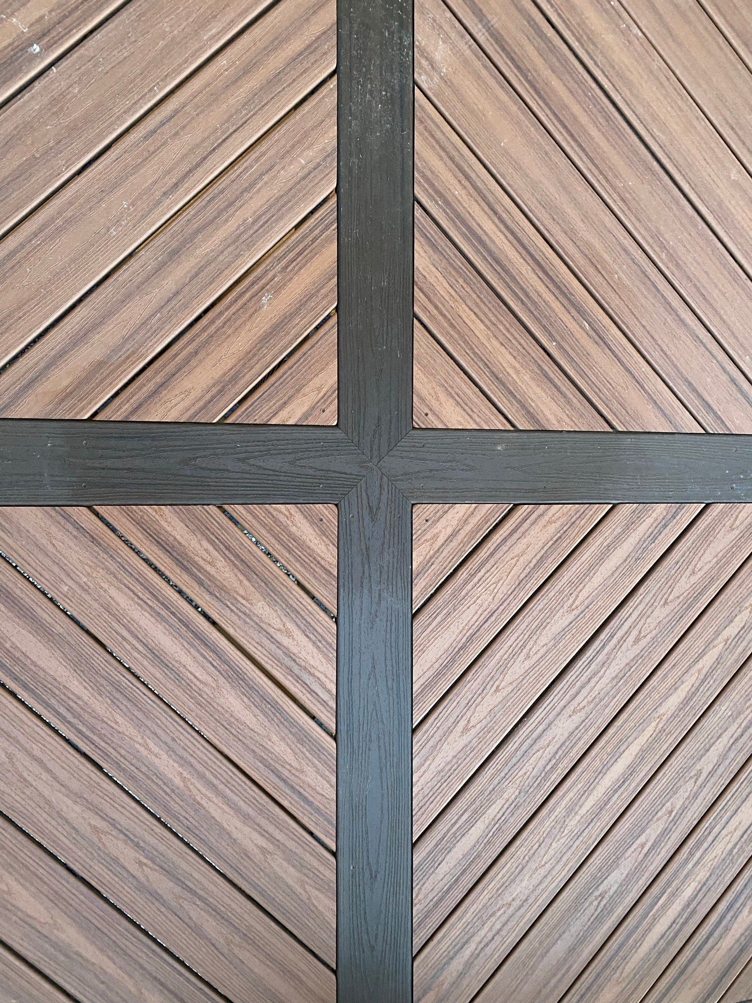 A close up of a wooden deck with a black cross in the middle.