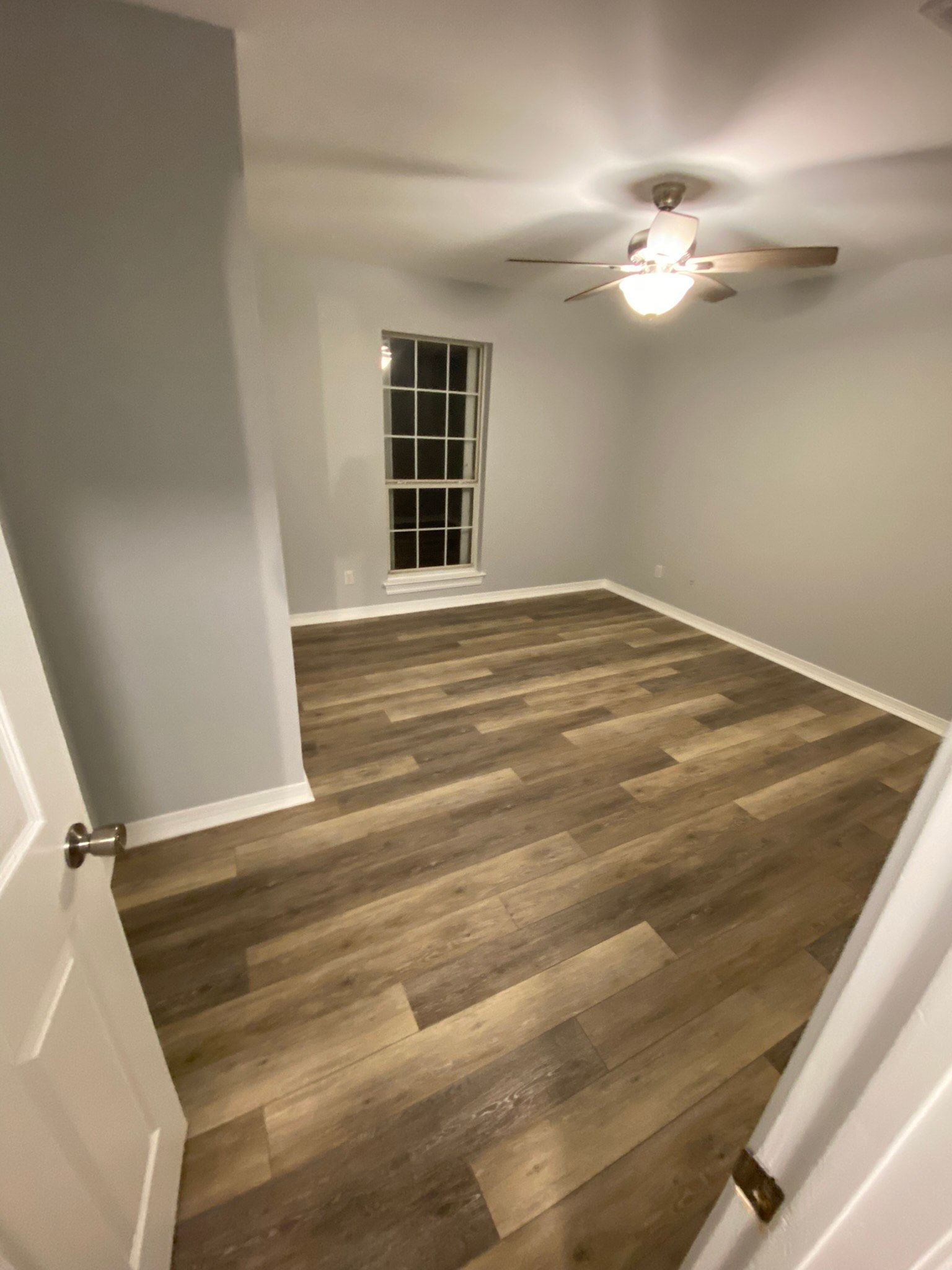 A bedroom with hardwood floors and a ceiling fan.