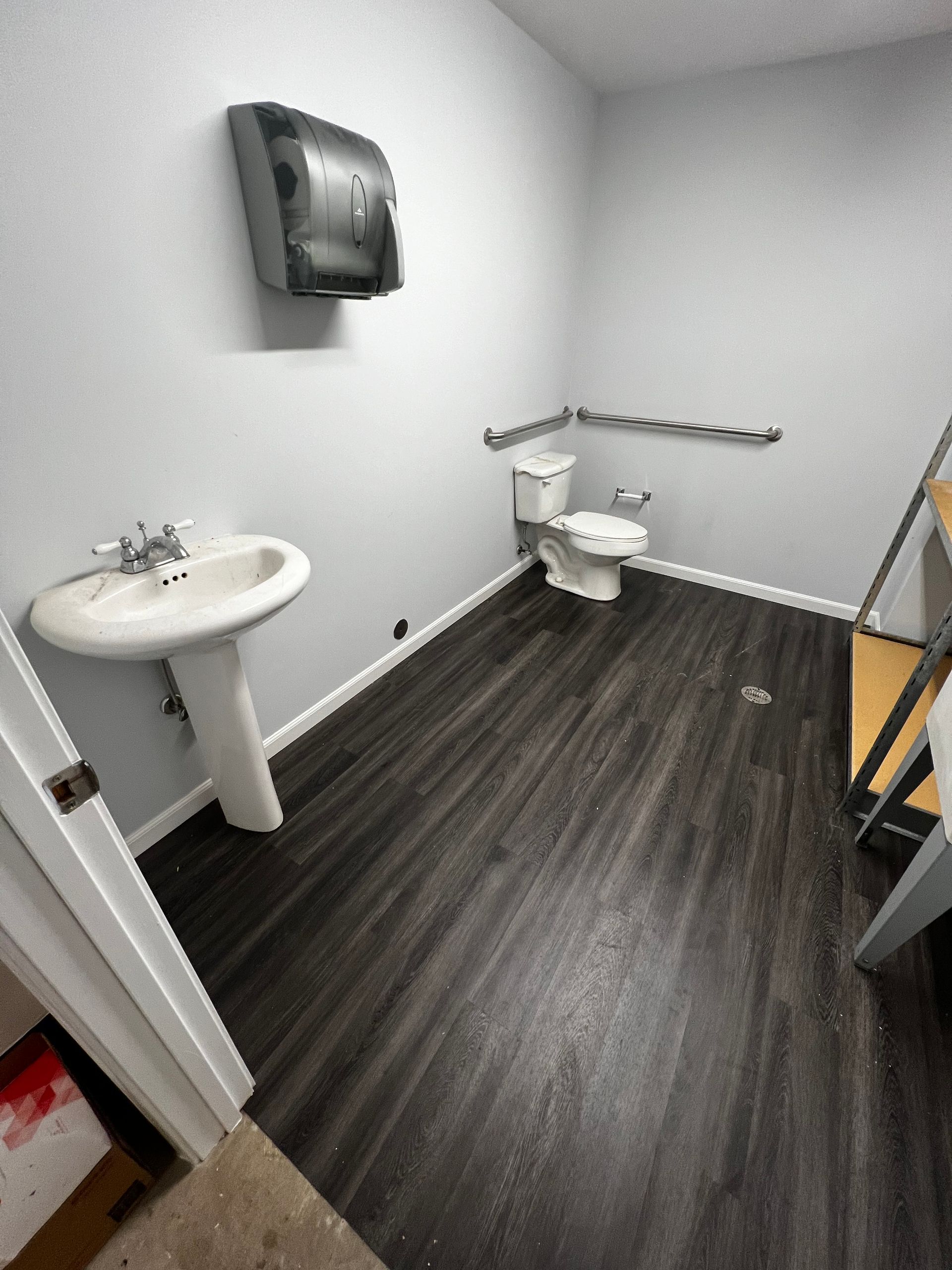 A bathroom with a toilet , sink and paper towel dispenser.