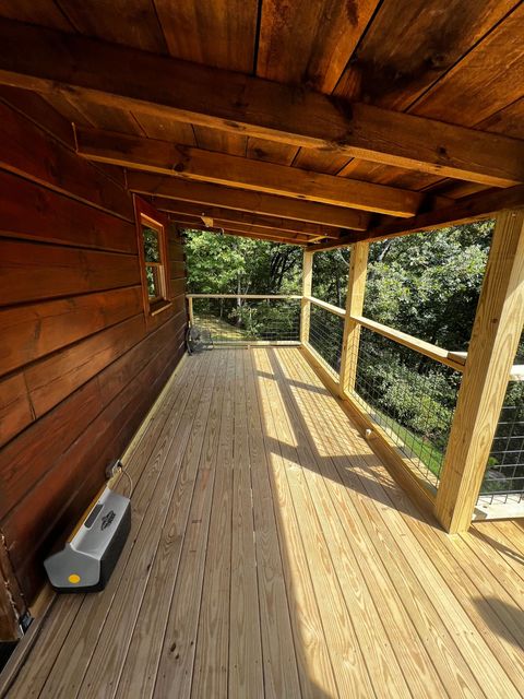 A wooden deck with a cooler on it and trees in the background.