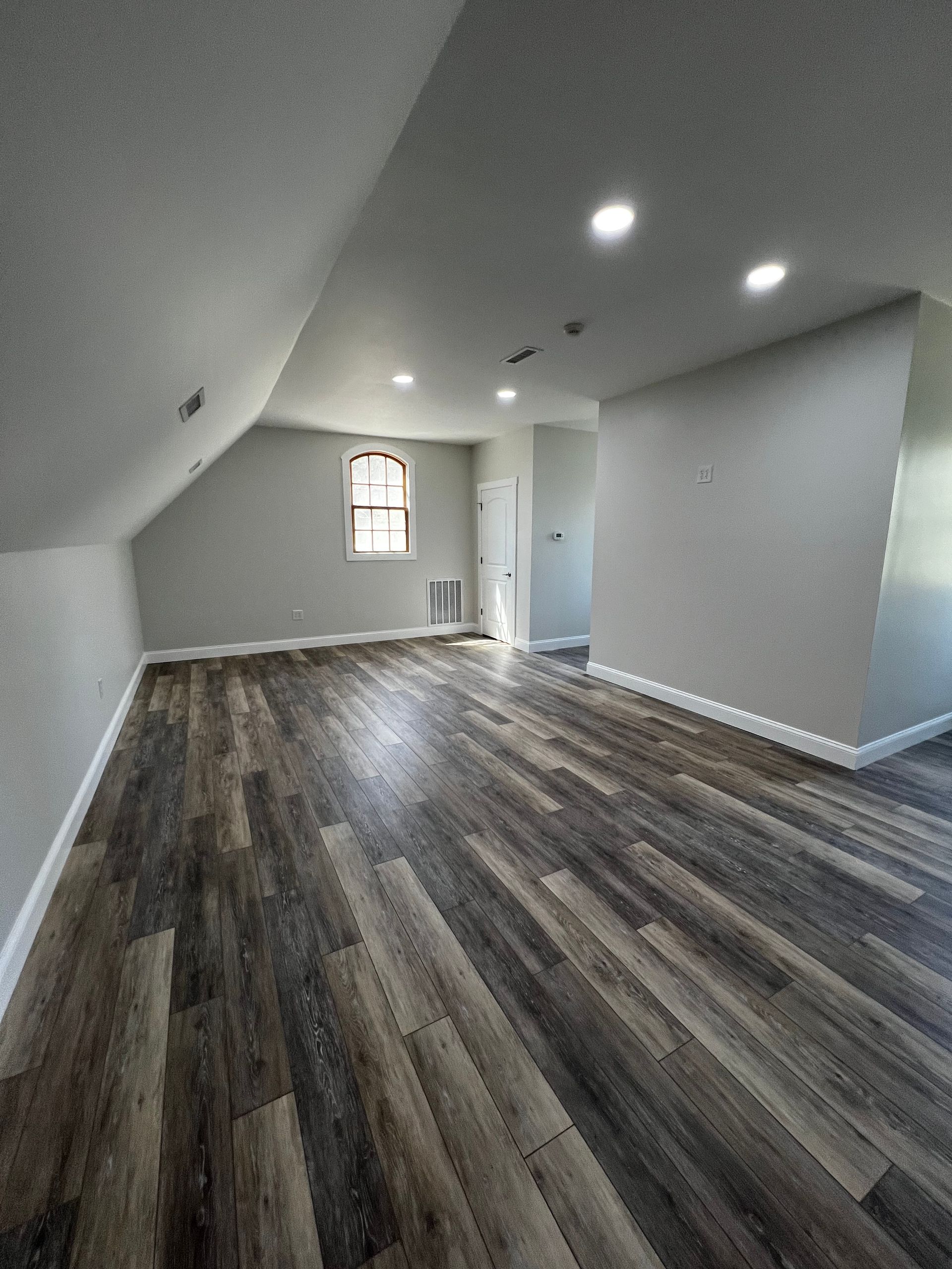 A large empty room with hardwood floors and a window.