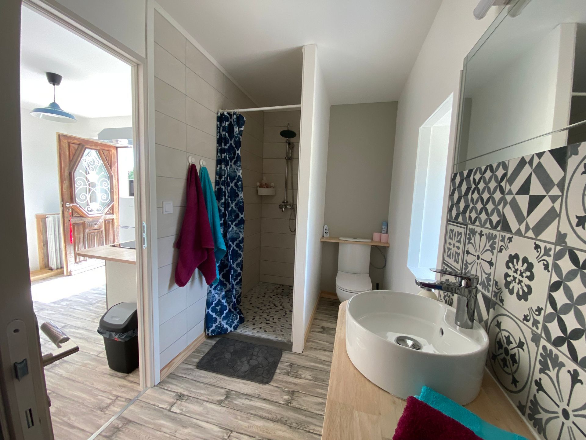 Vue d'une salle de bain avec une vasque ronde et des carrelages en azulejos avec des toilettes au fond.