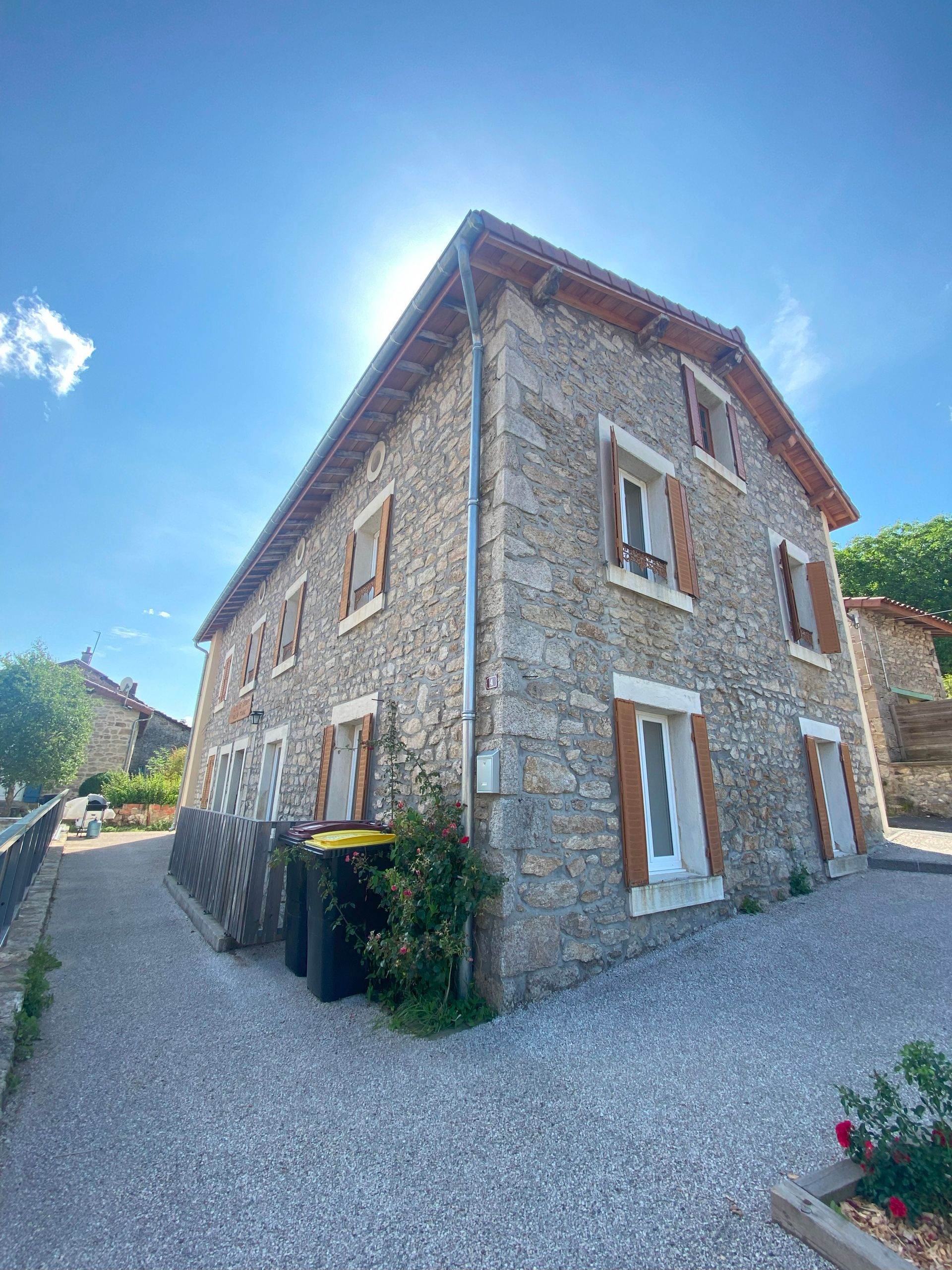 Une longue table à manger en bois est dressée pour un repas, avec assiettes, verres et ustensiles.