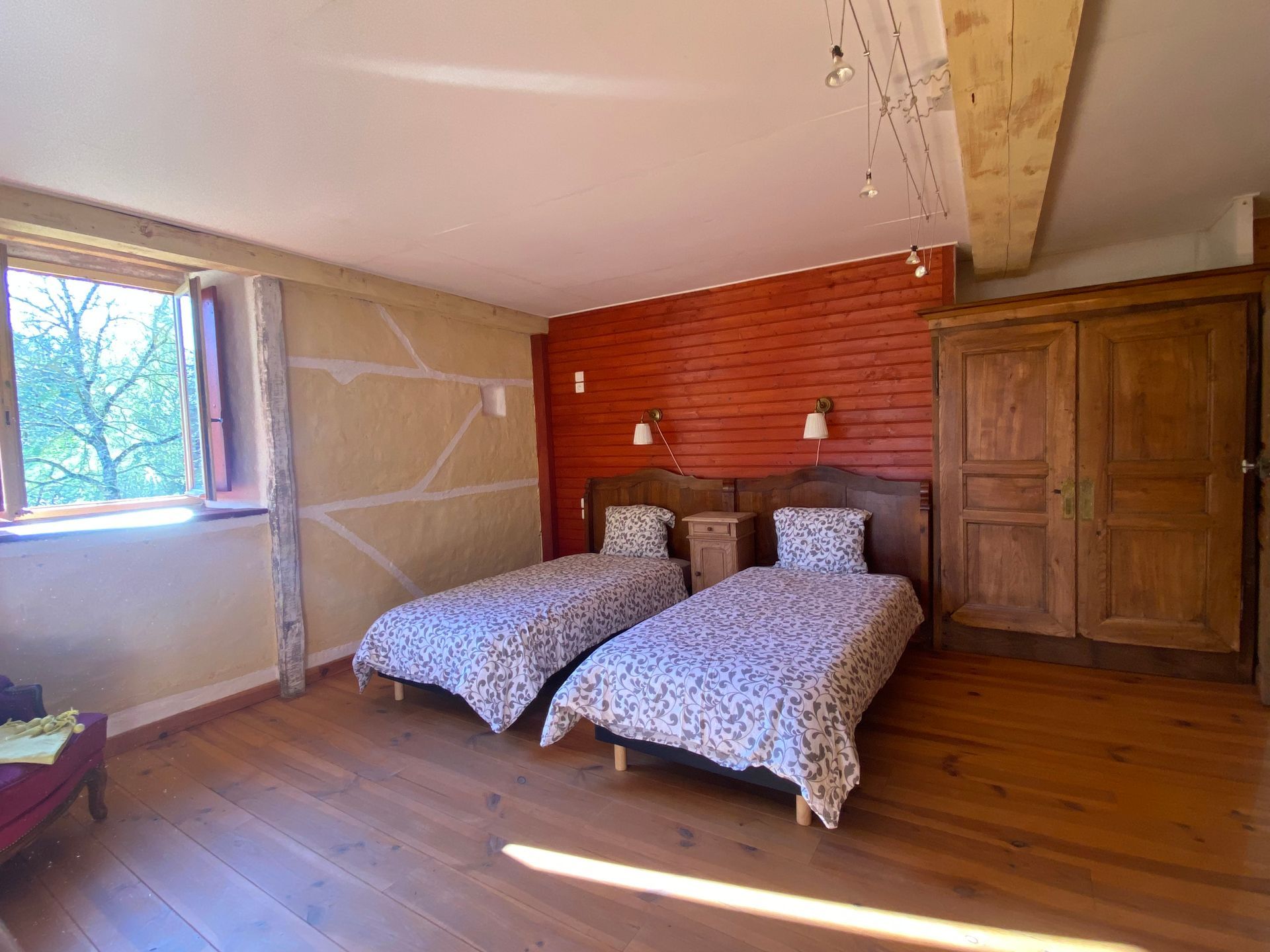 Chambre avec parquet et murs en bois, comprenant 2 lits et une table de nuit, un canapé, un fauteuil .