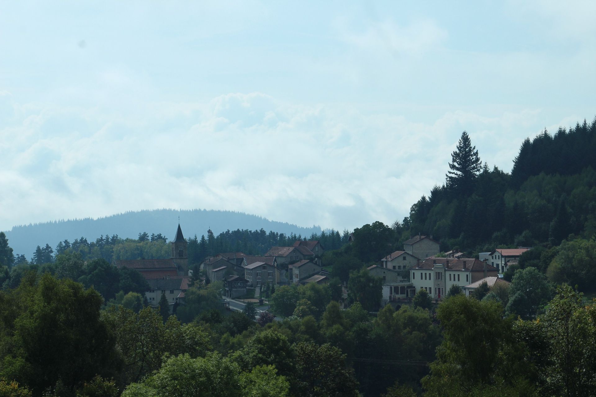Petit village de montagne entouré de verdure à flanc de montagne.