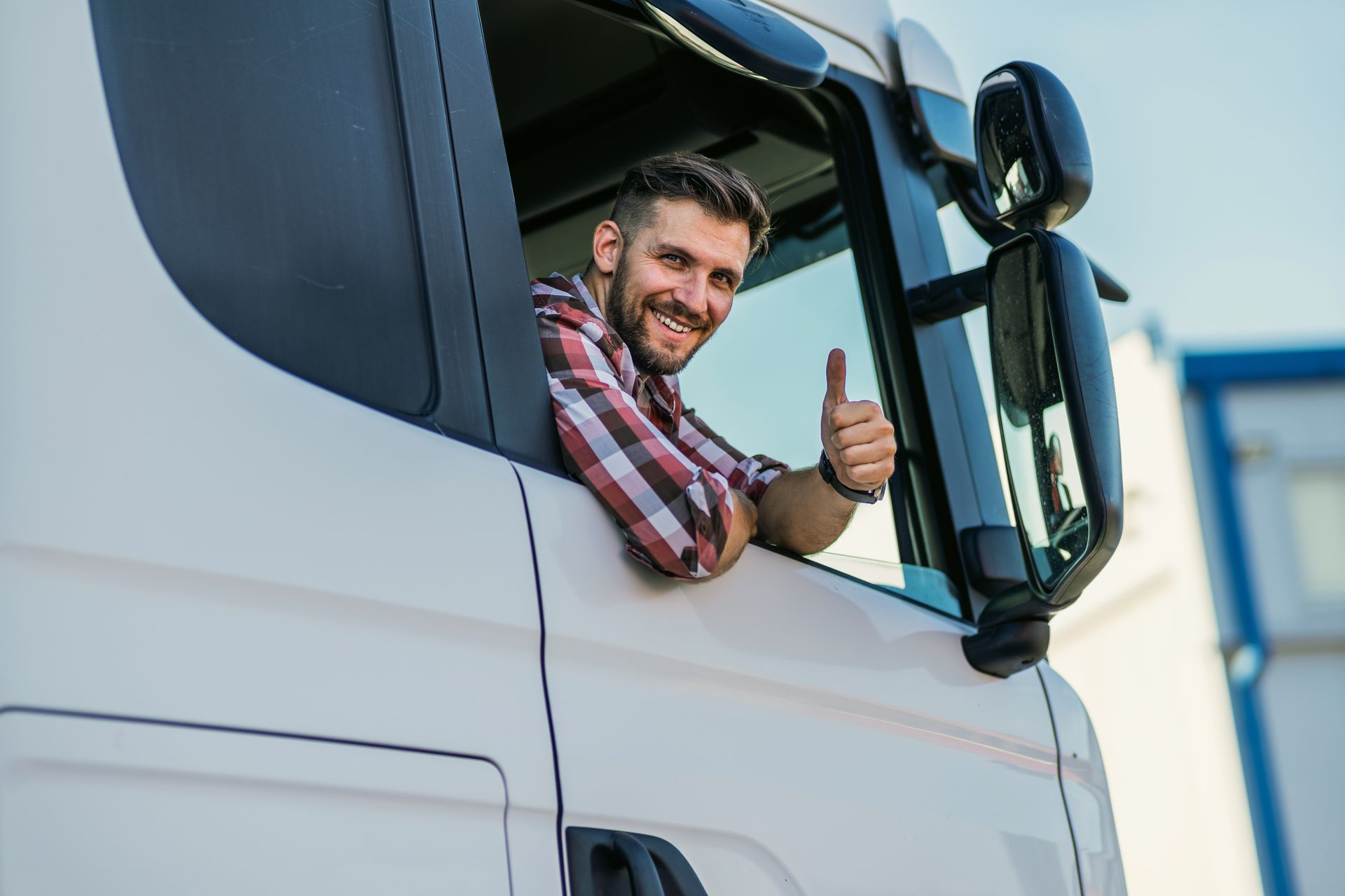 A man is giving a thumbs up from the window of a truck.