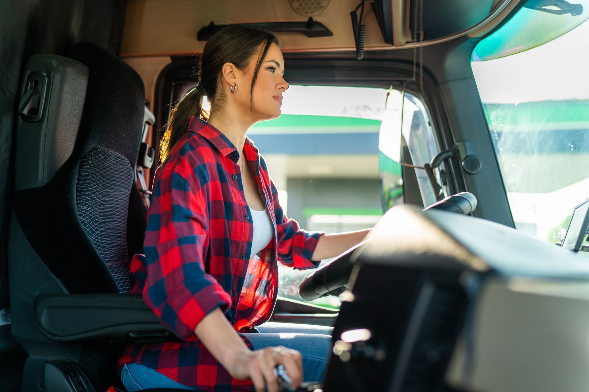 A woman is sitting in the driver 's seat of a semi truck.