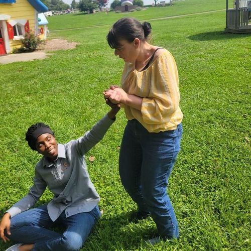 Developmentally disabled person holding hands with a seated support DSP outdoors