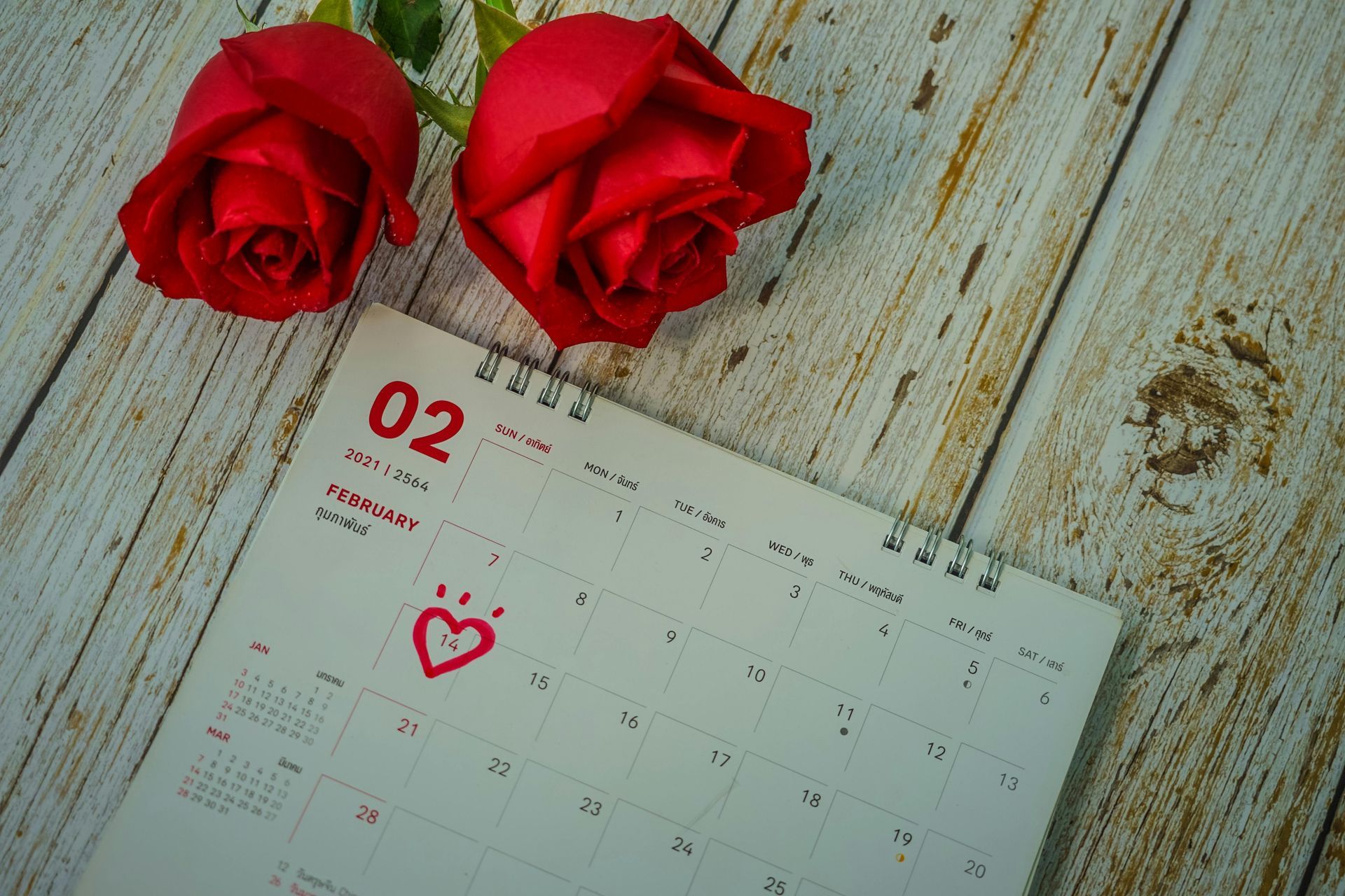 A rose flower next to a calendar displaying February