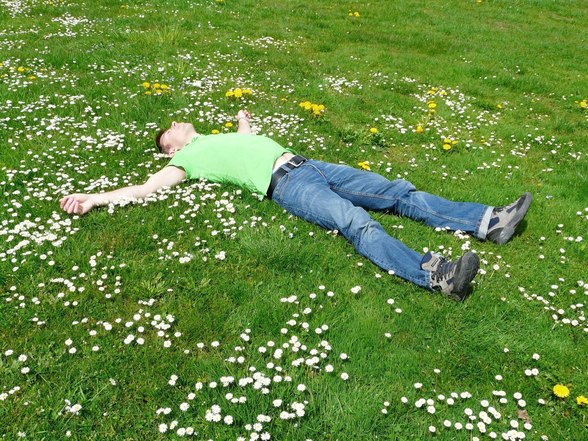 A person relaxing on grass with legs spread out