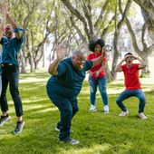 Developmentally disabled individual joyfully playing in a group with support from Direct Support Professionals (DSP)