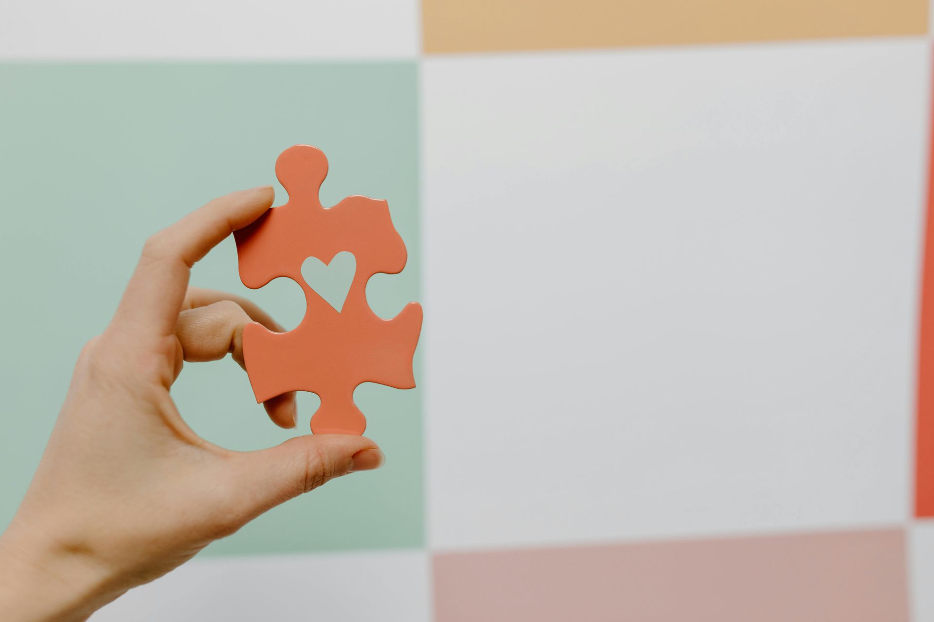 A hand holding a piece of puzzle with love symbol